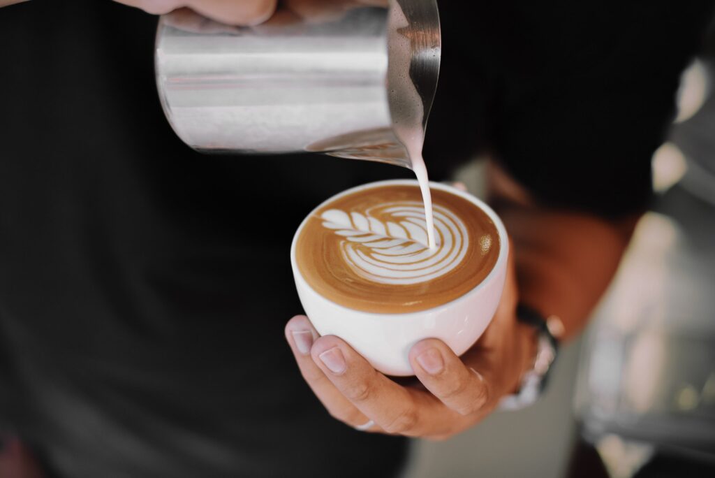 Nalewanie mleka i tworzenie latte art w filiżance kawy